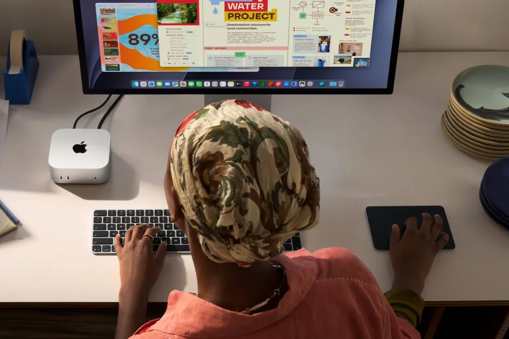 Una persona alla scrivania con un Mac mini collegato a un grande monitor esterno, vista dall’alto.