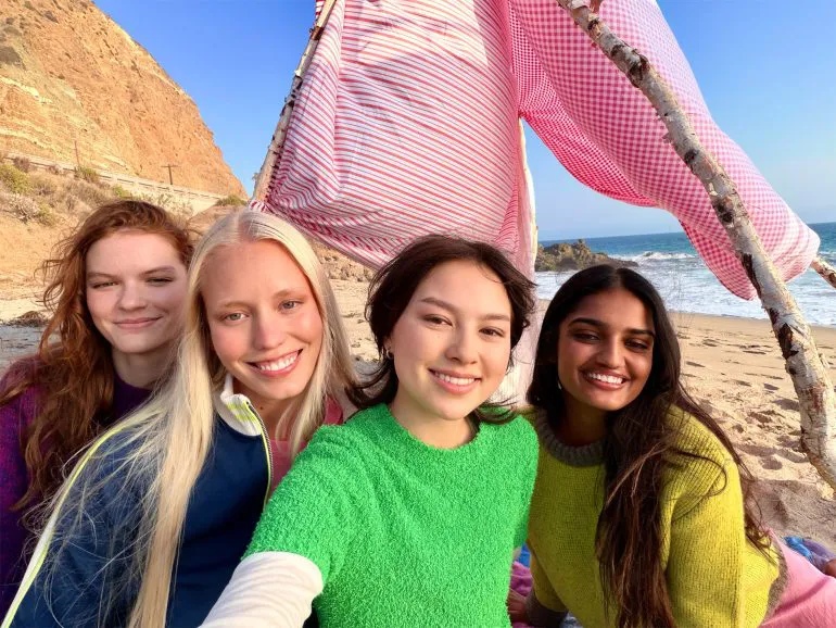 Un selfie di gruppo scattato con iPhone 17 con quattro persone in spiaggia